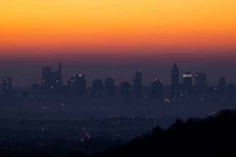 Shortly in front of sunrise, the sky behind the Frankfurt banking skyline turns yellow and orange,