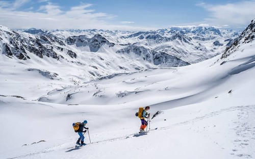 Two ski tourers in mountain landscape with snow, mountain panorama with summit of the Grisons Alps,
