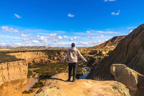 Tourist standing on a cliff with open arms, contemplating the breathtaking view of bardenas reales