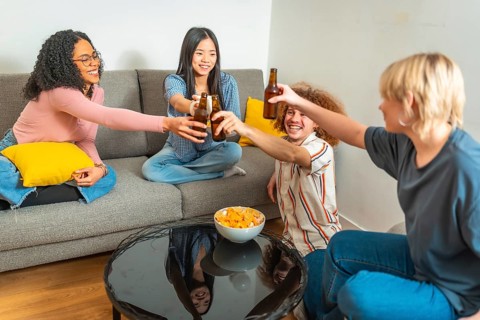 Group of young multi ethnic people having fun and toasting with beer bottles while sitting on a