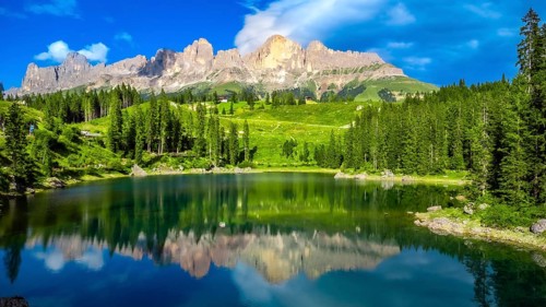 Stunning view of latemar mountain group reflecting in the emerald smooth water of lake carezza on a