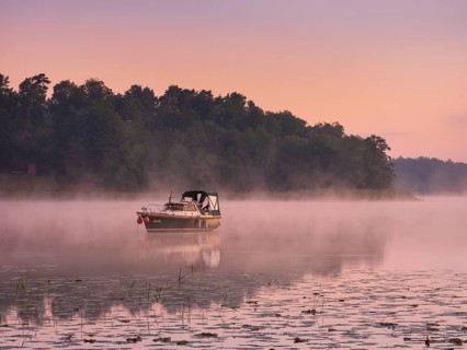 Morning atmosphere at Lake Grienerick, boat anchored, morning mist on the water, Rheinsberg,