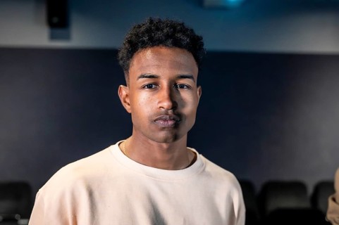 Portrait of a young man standing in a movie theater during a movie session, possibly participating