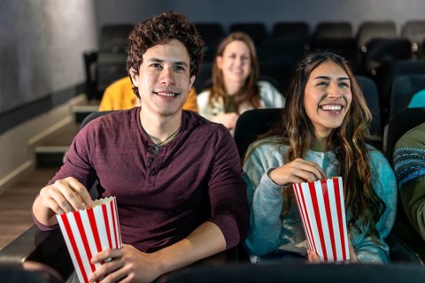Happy couple enjoying a movie night at the cinema, sharing popcorn and smiles while immersed in the