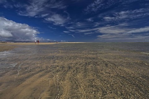 Wide beach Playa Risco del Paso, Playa de Sotavento with sea view, clouds in the blue sky and a