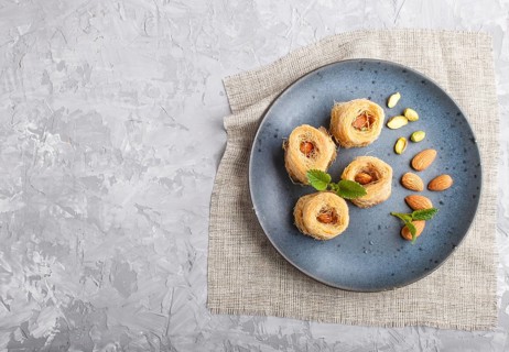 Kunafa, traditional arabic sweets in blue ceramic plate on a gray concrete background. top view,