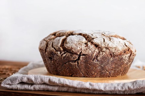 Yeast free homemade bread with whole rye and wheat grains on rustic wooden background. close up