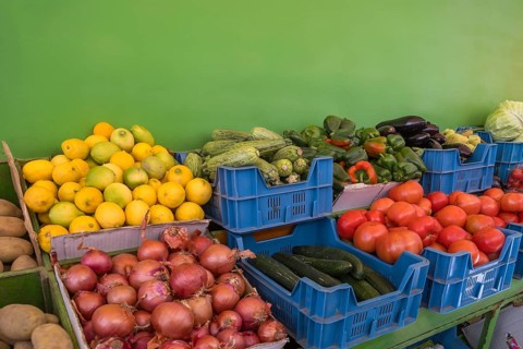 Market stall with various types of fruit and vegetables such as lemons, potatoes, onions, tomatoes,