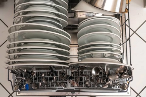 Dishwasher, full, with cleaned crockery, cutlery, cooking utensils