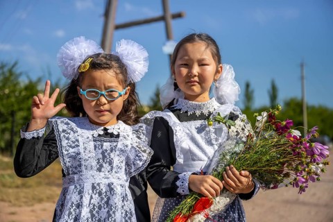 Schoolgirl with a bouquet of flowers on her first day at school, Issyk-Kul region, Kyrgyzstan, Asia