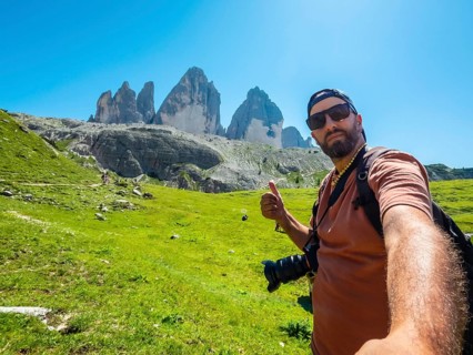 Photographer taking a selfie while hiking showing thumbs up sign with tre cime di lavaredo