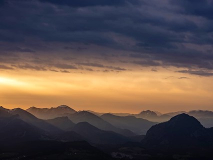 Alpine panorama under an overcast sky, illuminated by the sun through a gap in the clouds,
