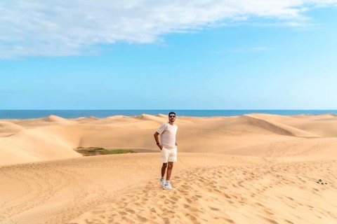 Tourist exploring the scenic landscape of maspalomas dunes with the ocean in the background