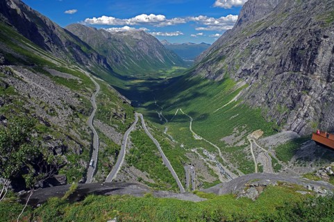 View over a winding mountain road and a narrow valley, rough rocks, small viewing platform,