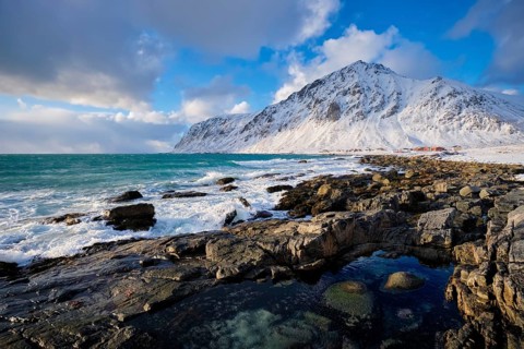 Beach of Norwegian sea on rocky coast in fjord on sunset in winter. Vareid beach, Lofoten islands,