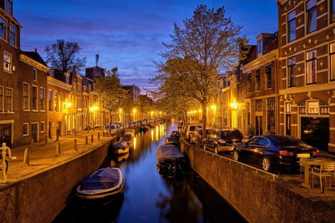 Typical Netherlands city view, canal with boats and houses illuminated in the evening. Haarlem,