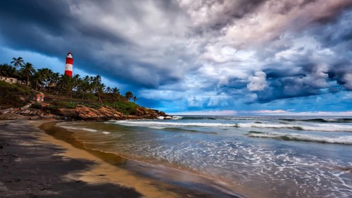 Panorama of gathering storm on beach and Kovalam (Vizhinjam) lighthouse on stormy sunset. Kerala,