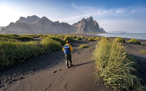 Tourist on a sand dune, Black beach with volcanic sand, Sand beach, Dunes with grass, Stokksnes