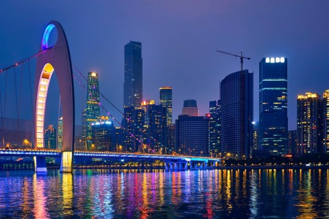 Guangzhou cityscape skyline over the Pearl River with Liede Bridge illuminated in the evening.