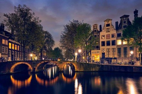 Night view of Amterdam cityscape with canal, bridge and medieval houses in the evening twilight