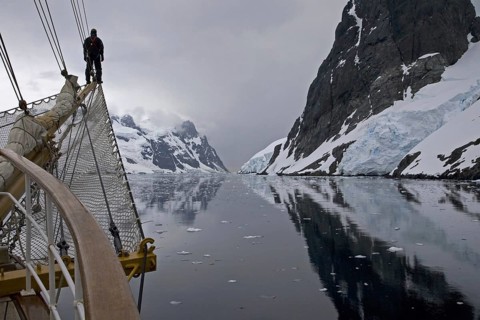 Sailing ship with man on bowsprit looking into the Lemaire Channel, Kodak Gap, Antarctica