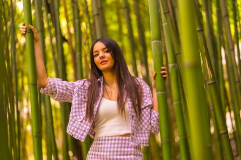 Young caucasian girl with a pink skirt in a bamboo forest. Enjoying the city on summer vacation in