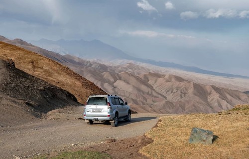 Off-road vehicle at the Tyibel Pass, mountain landscape of the Song Kul Too mountain range, Naryn