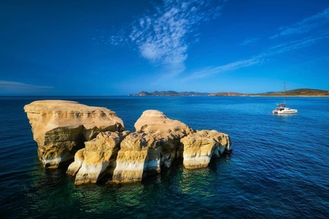 White rocks of famous tourist attraction of Milos island Sarakiniko beach and yacht boat at