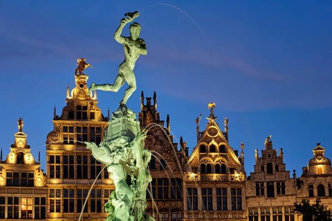 Antwerp famous Brabo statue and fountain on Grote Markt square illuminated at night and old houses.