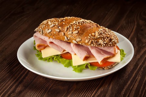 Ham sandwich with lettuce, cheese, tomato on plate on wooden table