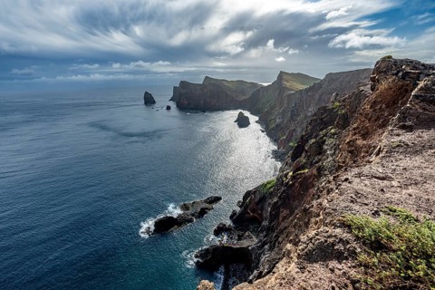 Red cliffs and rocks in the sea, coastal landscape with dramatic sky, Ponta de São Lourenço,