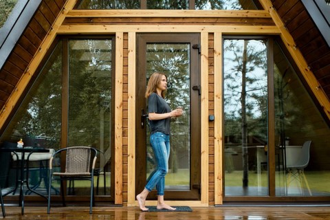 Barefoot woman came out on the wet terrace of a triangular summer house after the rain with a cup