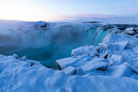 Icefall at the edge of the Godafoss waterfall at dawn, snow-covered landscape, Northern Iceland