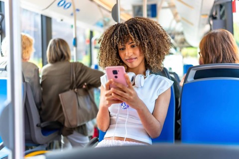 Young beauty latin woman with curly hair and casual clothes using phone distracted sitting on