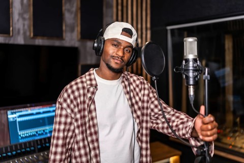 Young artist wearing headphones recording vocals for new song or album in professional recording