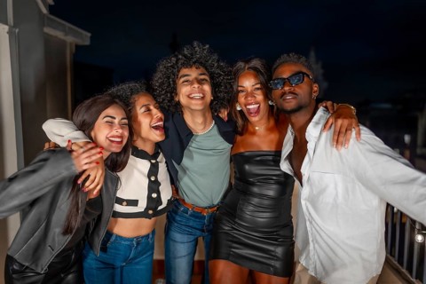 Portrait of multi-ethnic group of males and females friends embracing from the shoulder partying at