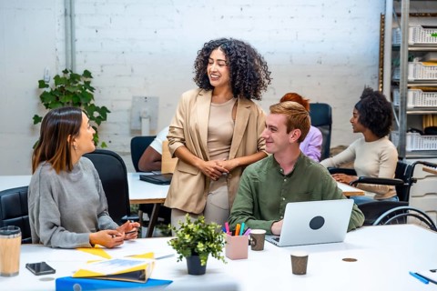 Three diverse females and male coworkers talking distracted in a modern coworking room