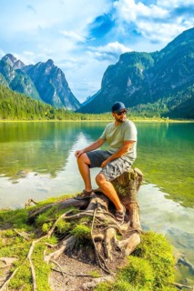 Tourist enjoying the scenic view of lake dobbiaco and the dolomites mountains while sitting on a