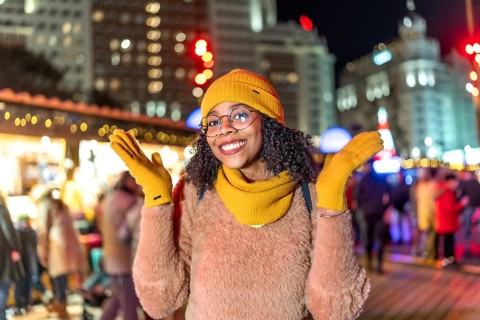 Young woman wearing yellow winter clothes enjoying christmas market in plaza de espana, madrid, at