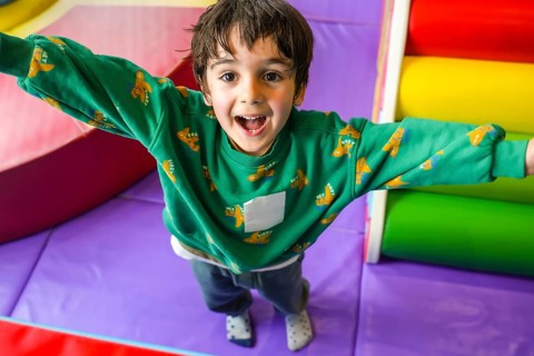 Preschooler enjoying playtime in colorful indoor playground, expressing pure happiness and