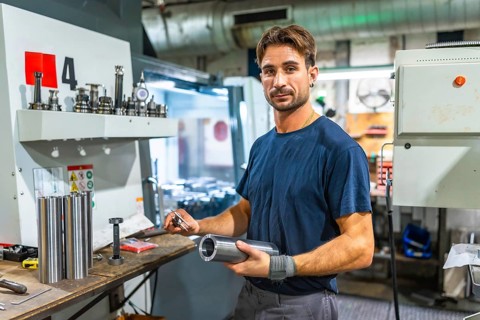 Portrait of a young operator working in metal pieces in a factory