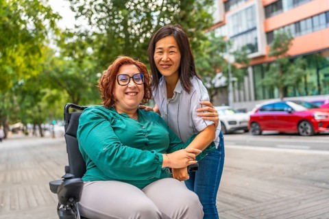 Portrait of a happy caucasian adult woman with disability sitting on electric wheelchair and her