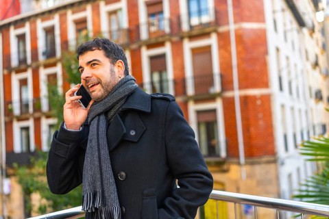 Adult caucasian man in elegant warm clothes talking to the mobile standing in the city