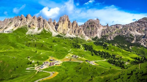 Stunning aerial view of the picturesque gardena pass winding through lush green valleys, embraced