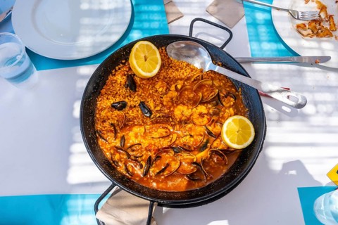 Steaming seafood paella featuring mussels, shrimps, clams, and lemon wedges served in a traditional