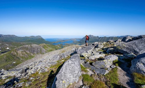 View of mountains and fjord landscape, mountaineer at the summit of Rundfjellet, Svolvaer,