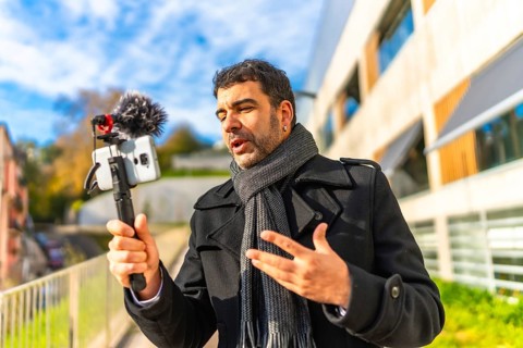 Adult male vlogger in elegant winter clothes recording online video in the city