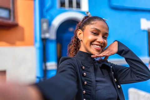 Beauty flirty african american woman gesturing hand down chin smiling while taking a selfie in a