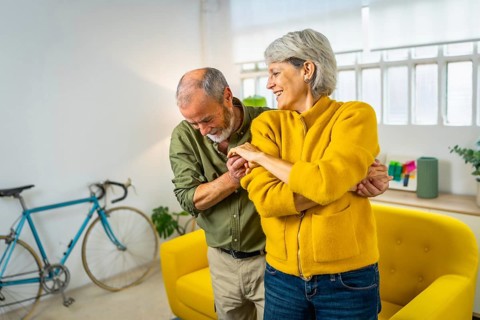 Happy mature couple dancing together and smiling at home