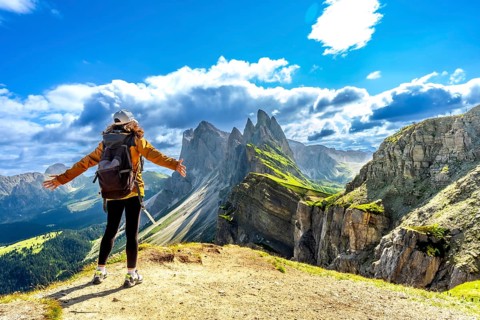 Hiker with open arms enjoying the breathtaking view of the odle mountains in seceda, dolomites,